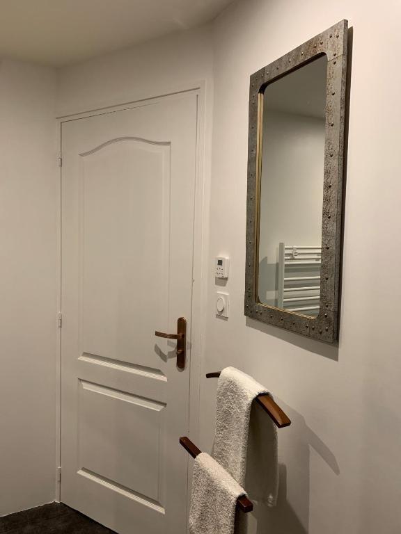 a bathroom with a white door and a mirror at La coccinelle in Noyarey