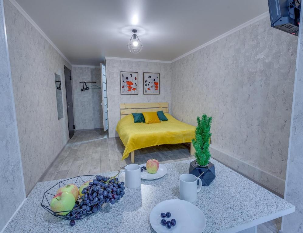a room with a yellow bed and a table with fruit at YourHouse на Розыбакиева Утепова недалеко от Меги in Almaty
