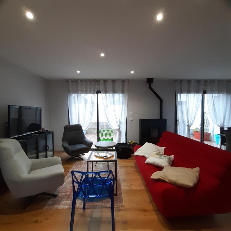 a living room with a red couch and two chairs at Maupy in Ploemeur