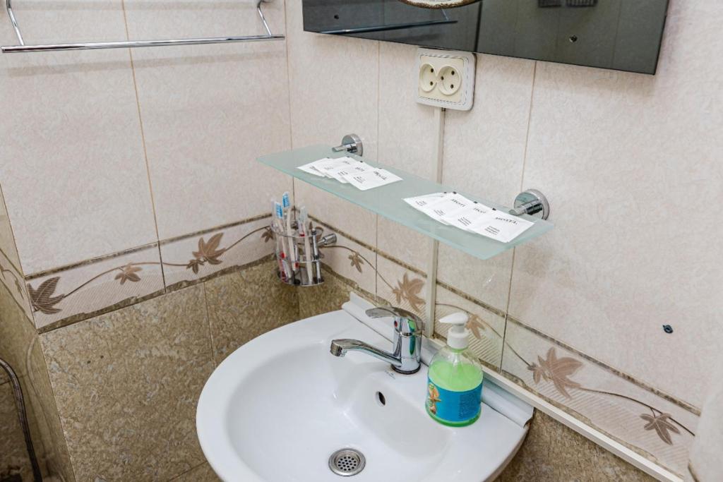ein Badezimmer mit einem Waschbecken und einer Seifenflasche darauf in der Unterkunft Книжный Город in Almaty
