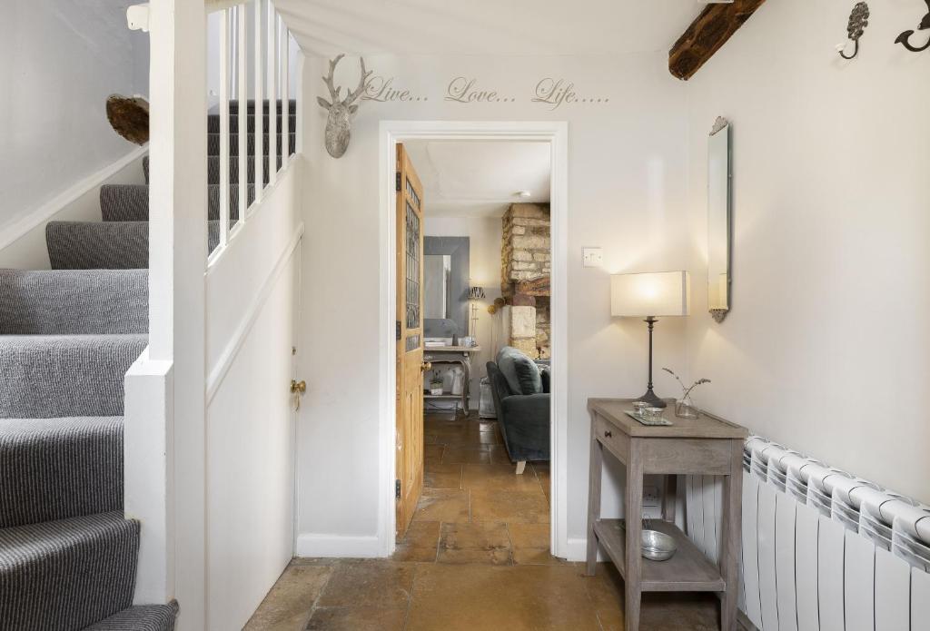 a hallway with stairs and a table with a lamp at Corner Cottage in Adlestrop