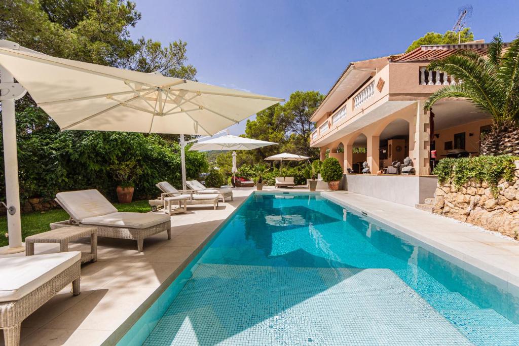 uma piscina com cadeiras e um guarda-sol ao lado de uma casa em Villa Es Pont, bis 10Pers, BBQ em Son Vida