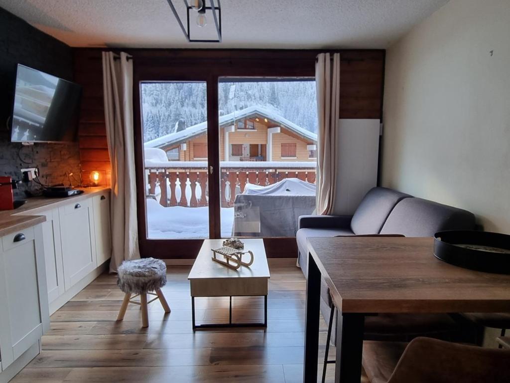 sala de estar con sofá, mesa y ventana en Appartement Châtel, 2 pièces, 4 personnes - FR-1-198-222, en Châtel