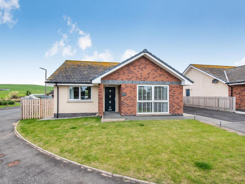 een huis met een grasveld ervoor bij Oystercatcher in Drummore