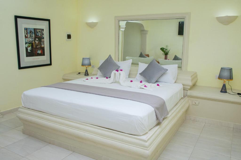a bedroom with a large white bed with a large mirror at Aparthotel Castillo Real in Punta Cana
