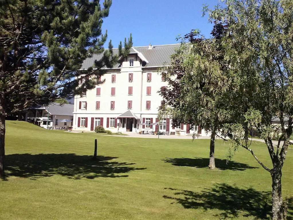 ein großes weißes Gebäude mit Bäumen davor in der Unterkunft Best Western Grand Hotel de Paris in Villard-de-Lans