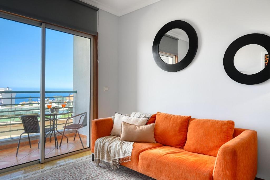 een oranje bank in een woonkamer met balkon bij Forum Escape, a Home in Madeira in Funchal