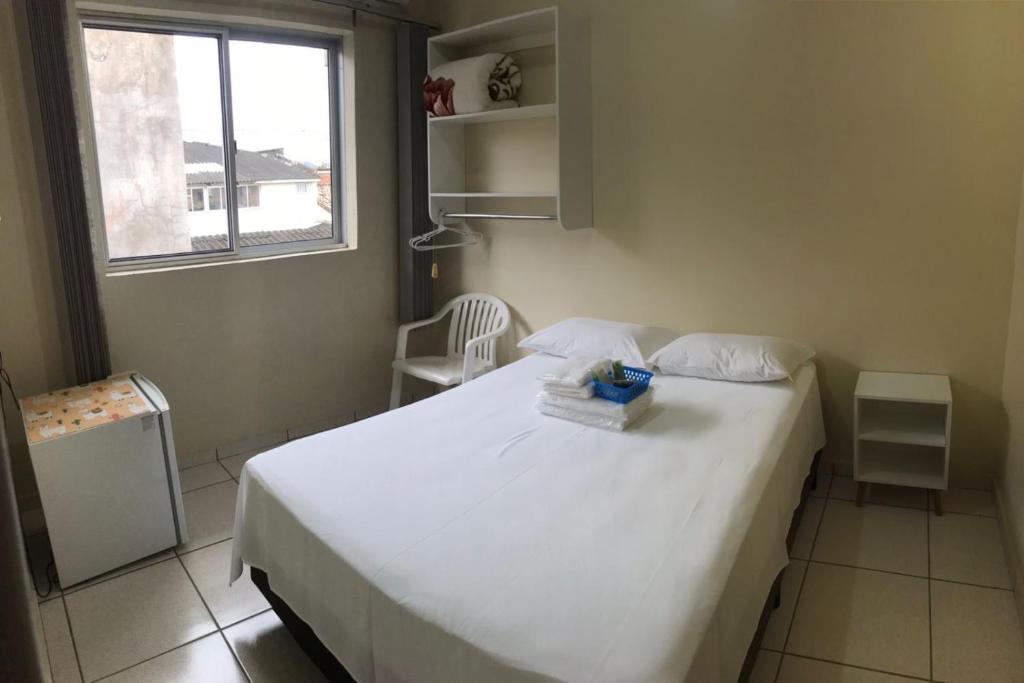 a bedroom with a white bed and a window at Stela Maris in Guaratuba