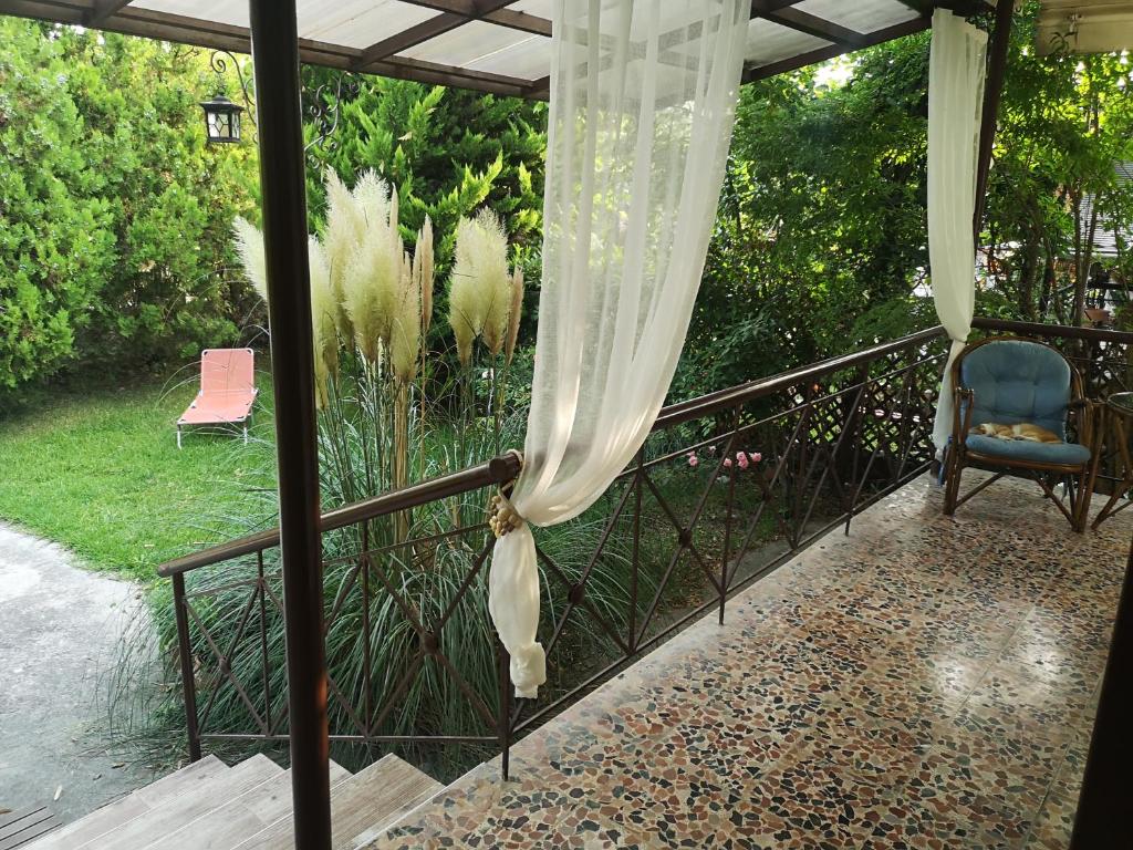 a balcony with a curtain and a chair on a porch at Bamboo gardens in Nea Irakleia