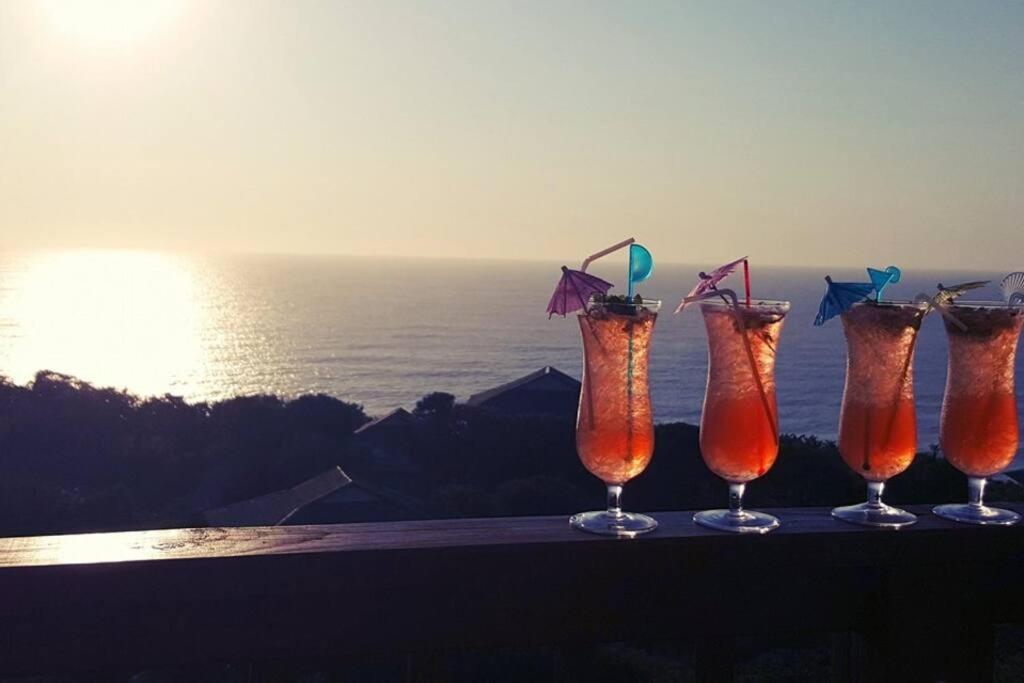 un grupo de cuatro bebidas sentado en una cornisa cerca del océano en Campismo Ninho Villa 26 - Ponta Malongane en Ponta Malangane