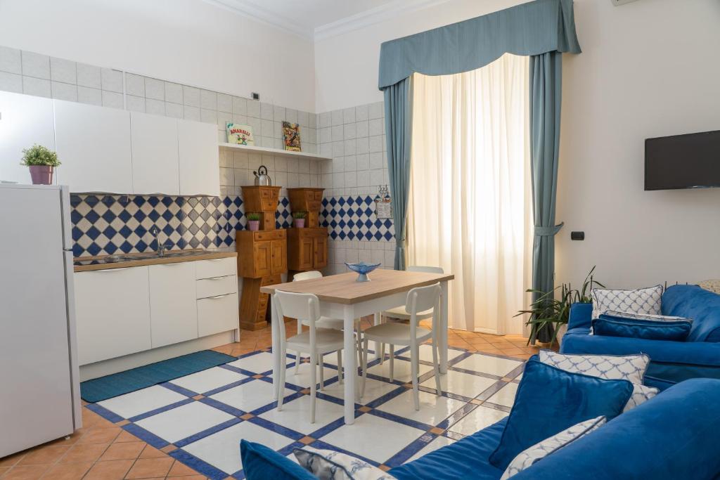 eine Küche und ein Wohnzimmer mit einem Tisch und einem blauen Sofa in der Unterkunft My Place Apartment in Castellammare di Stabia