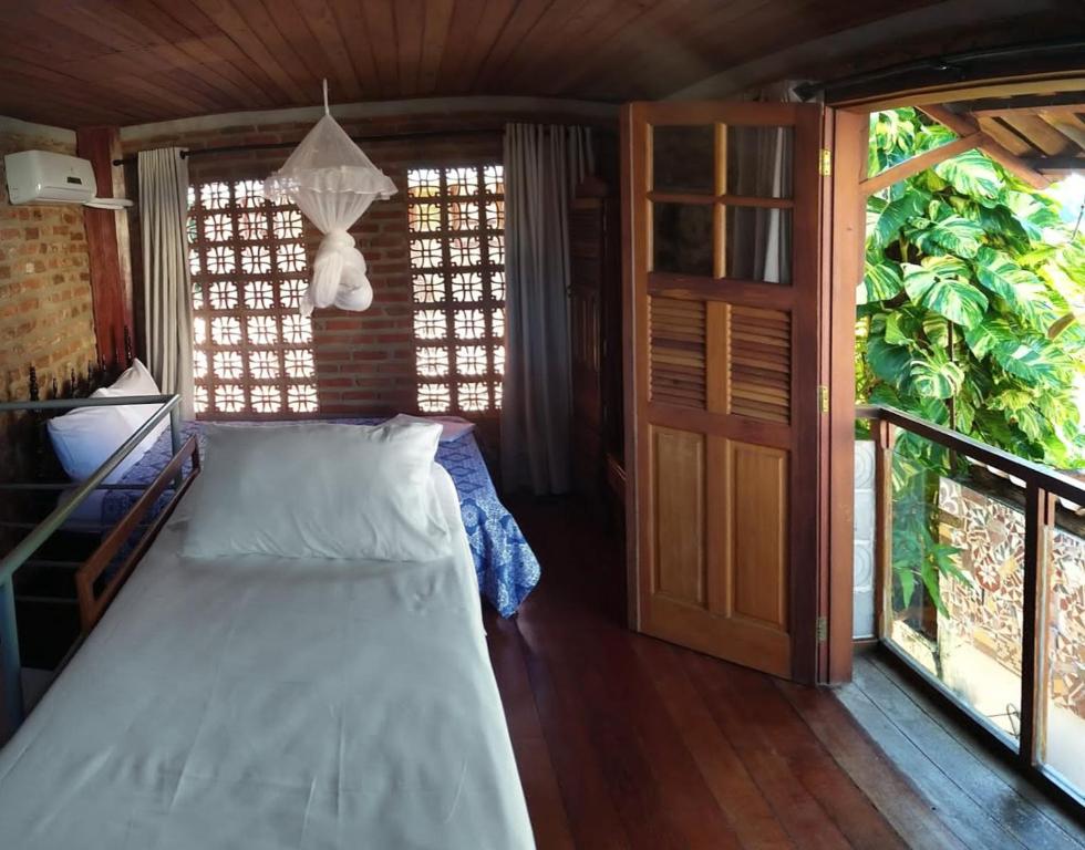 een slaapkamer met een bed en een groot raam bij Chalés na Hora in Olinda
