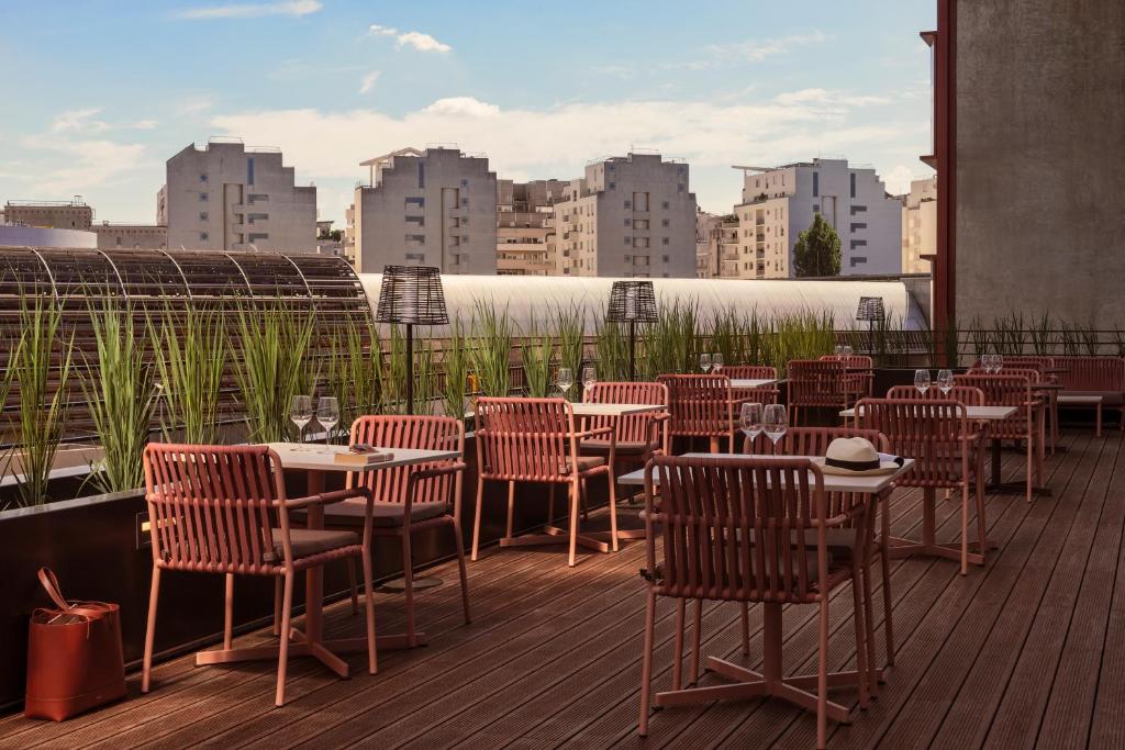 a restaurant with tables and chairs on a deck at OKKO Hotels Paris La Défense in Nanterre