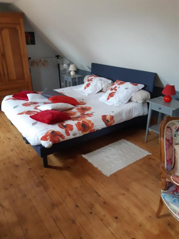 Un dormitorio con una cama con almohadas rojas. en Les Coquelicots, en Saint-Urbain