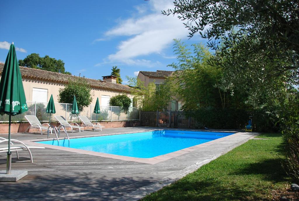 una piscina en un patio con sillas y sombrillas en Hôtel Le Barry, Toulouse Nord, en Gratentour