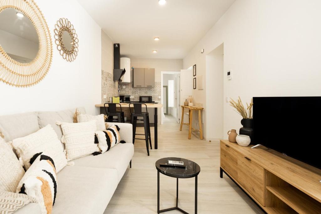 - un salon avec un canapé blanc et une télévision dans l'établissement Apartamento Mucha Vida Little Apartments, à Cadix