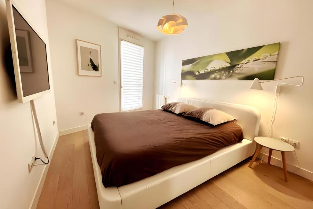 a bedroom with a bed and a flat screen tv at Chambre d'hôte Naos Homestay in Boulogne-Billancourt