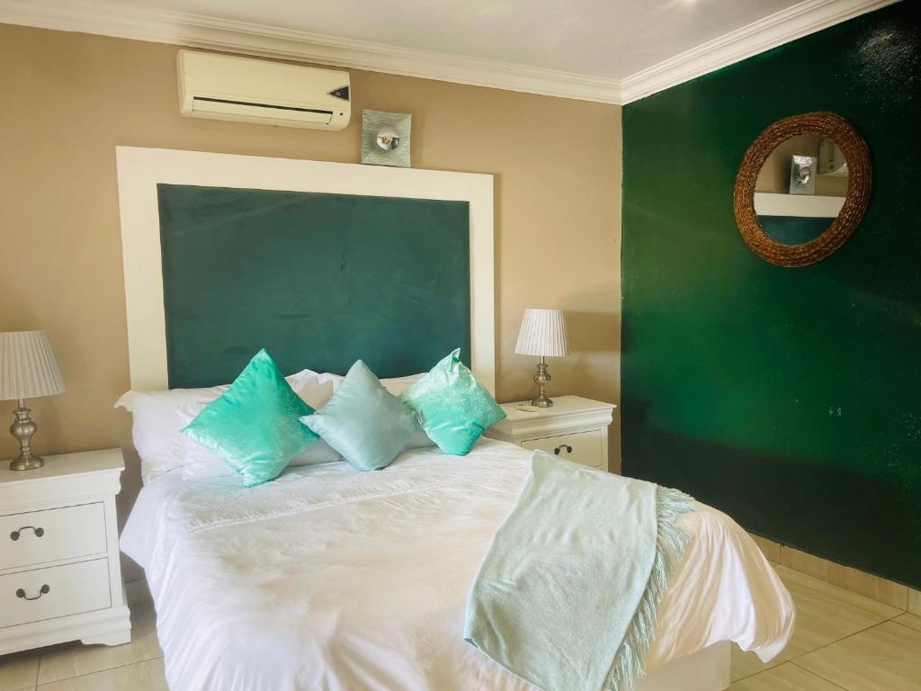 a bedroom with a green wall and a bed with blue pillows at The Grace Villa Guesthouse in Nelspruit