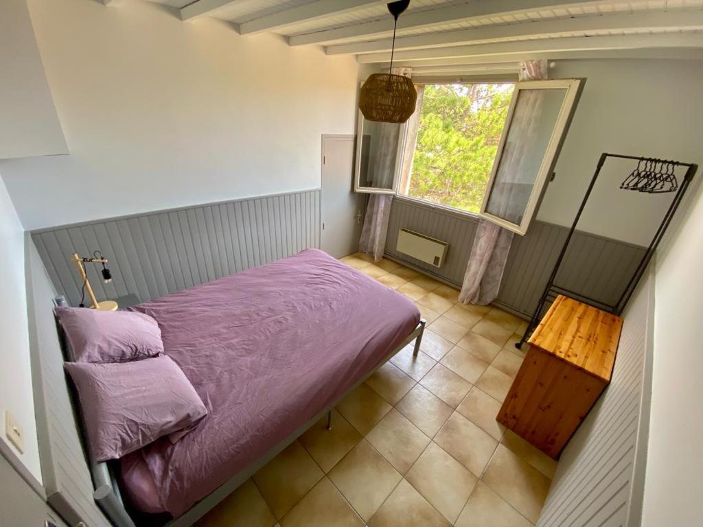 sypialnia z fioletowym łóżkiem i oknem w obiekcie Belle et grande villa pour des séjours en famille et entre amis w mieście Cruscades