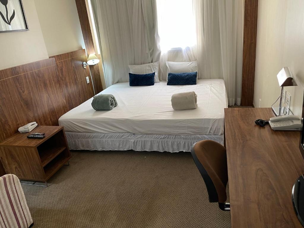 a hotel room with a large bed with blue pillows at PROMOÇÃO EXECUTIVA COM BANHEIRA E FLATS SEM BANHEIRA- Melhor Hotel De Taguatinga in Taguatinga