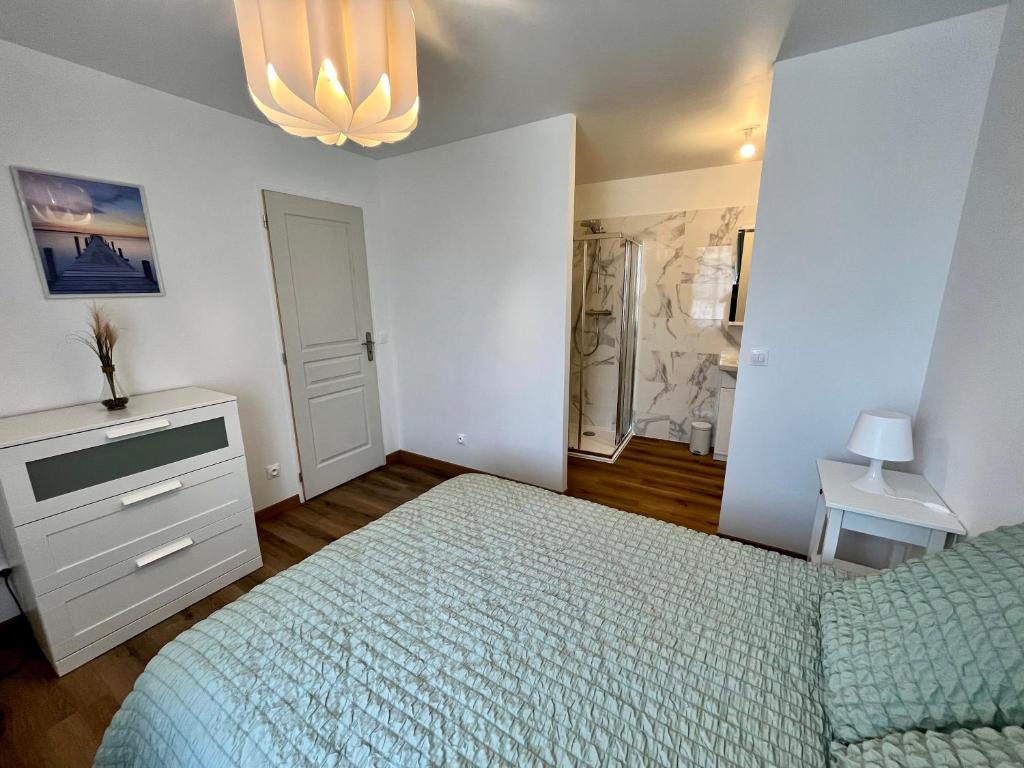 a bedroom with a bed and a chandelier at La Pause Cosy in Champagne-sur-Oise