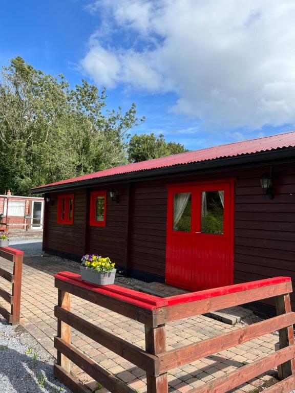 Cabaña pequeña con puerta roja en un banco de madera en Red Squirrel Lodge, en Galway