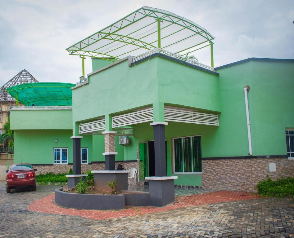 a green building with a car parked in front of it at Asaba Gardens and Resort in Asaba
