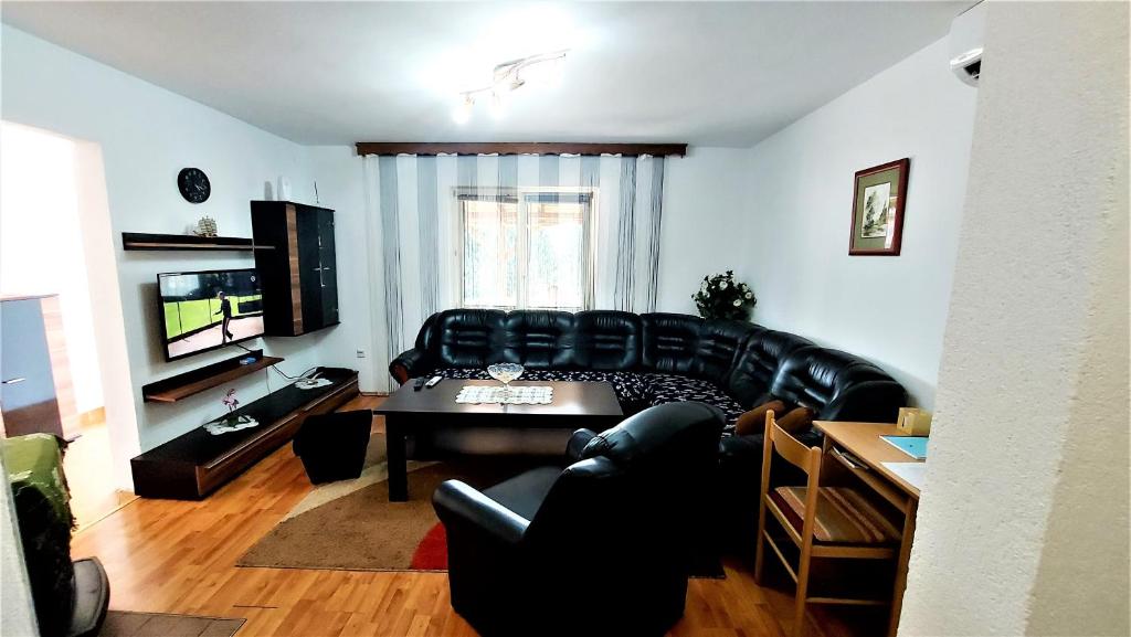 a living room with a black leather couch and a table at Holiday house with a big garden and free parking 
