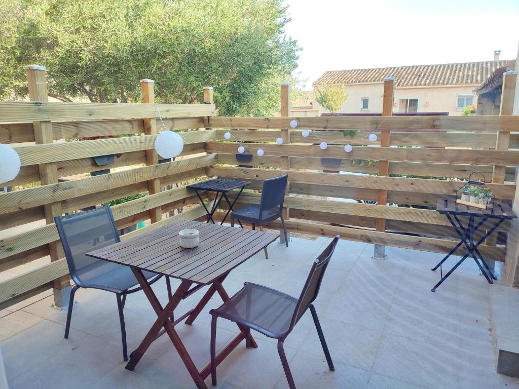 un patio con 2 mesas y sillas y una valla de madera en Studio R Homps en Homps