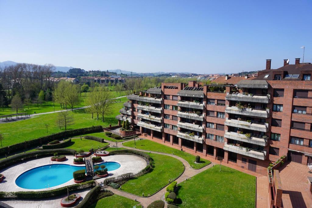 an apartment building with a swimming pool and a park at Estudio frente al Parque Fluvial con garaje in Gijón