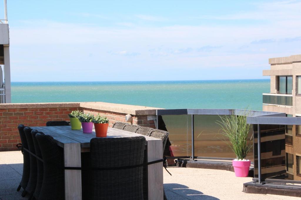 a table and chairs on a balcony with the ocean at Duplex Penthouse Plaza in De Panne