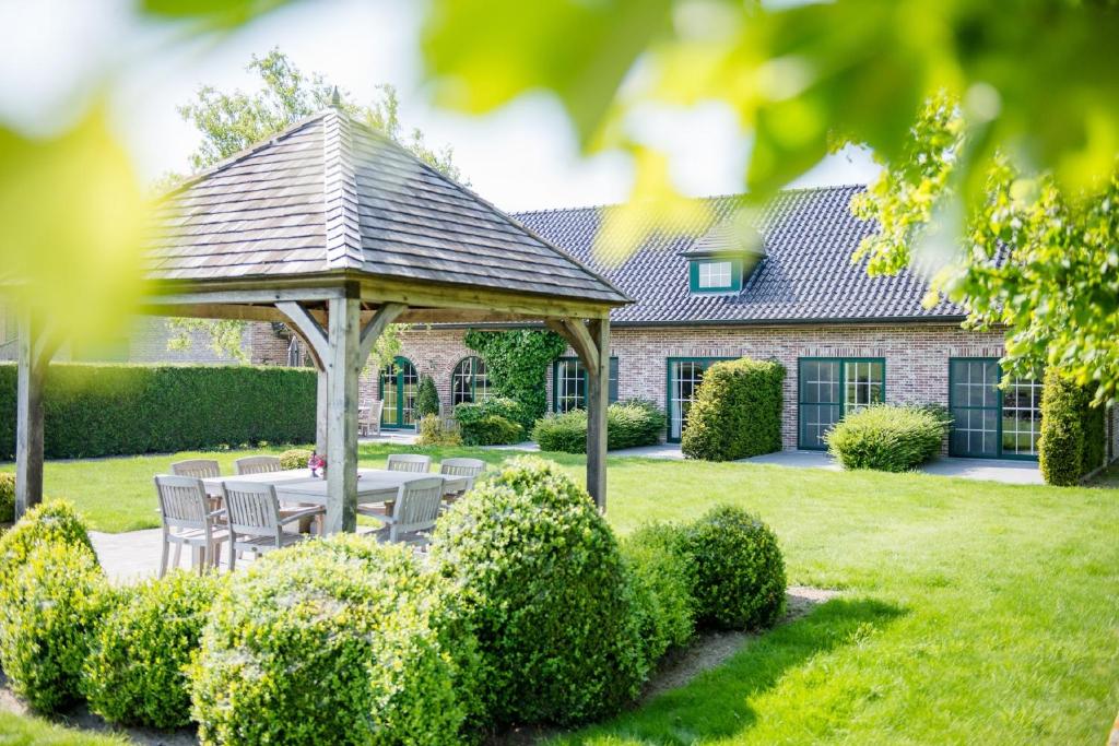 een tuinhuisje met een tafel en stoelen in de tuin bij B&B De Bergvallei in Oedelem