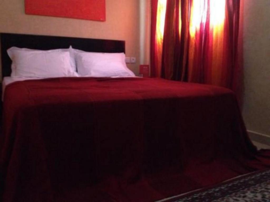 een bed met rode lakens en kussens in een slaapkamer bij Ali Appartement in Essaouira