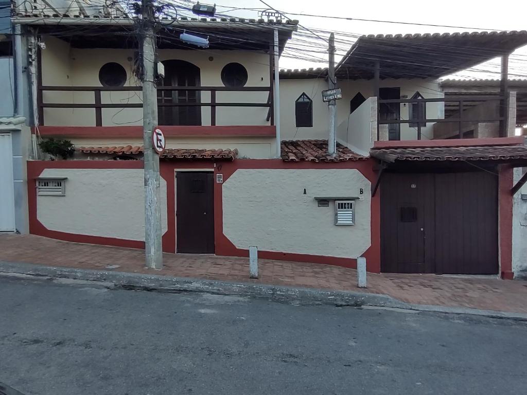 un edificio rojo y blanco con una puerta y una calle en kitnet A com piscina, en Arraial do Cabo