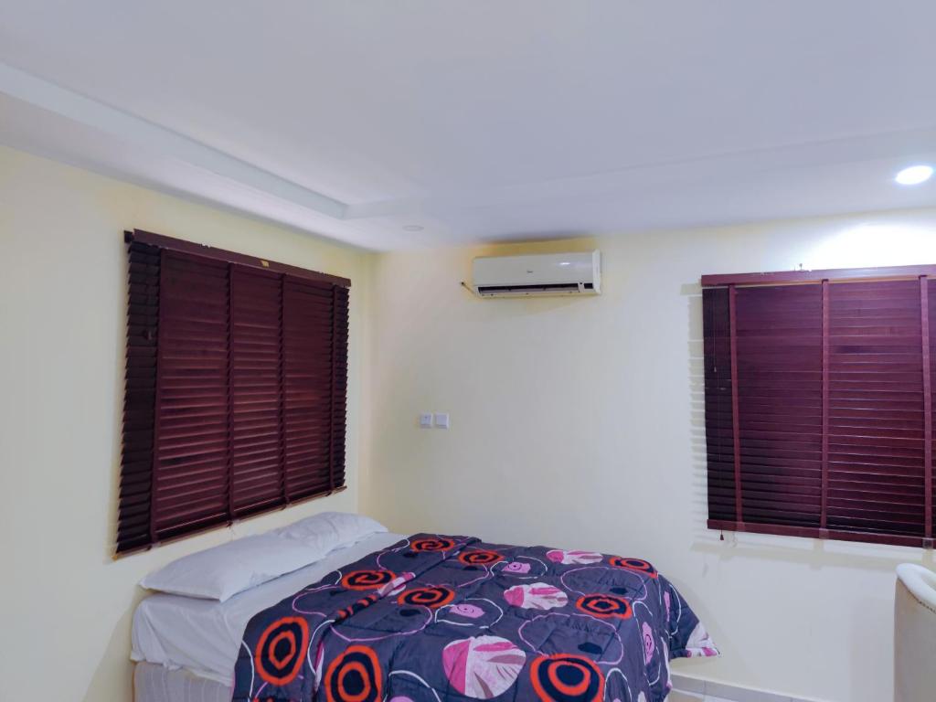 a bedroom with a bed and two windows at Abuja Apartments 24 in Abuja