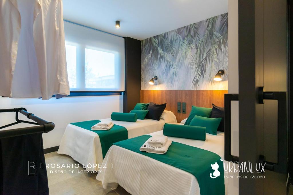 Habitación con 2 camas con cojines verdes en Urbanlux Olimpia Pet Friendly, en Albacete
