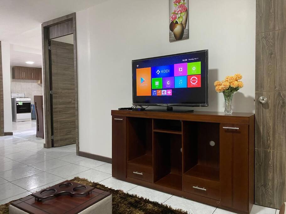 TV de pantalla plana en la parte superior de un centro de entretenimiento de madera en Confort Home - Apartamento ¨Dalias¨, en Baños