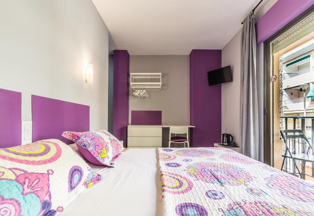a bedroom with purple and white walls and a bed at Hostal Tropical in Almuñécar
