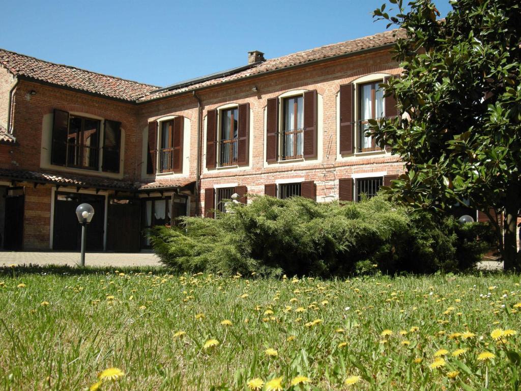 un antiguo edificio de ladrillo con un campo de hierba en Da Nonna Carla, en Alfiano Natta