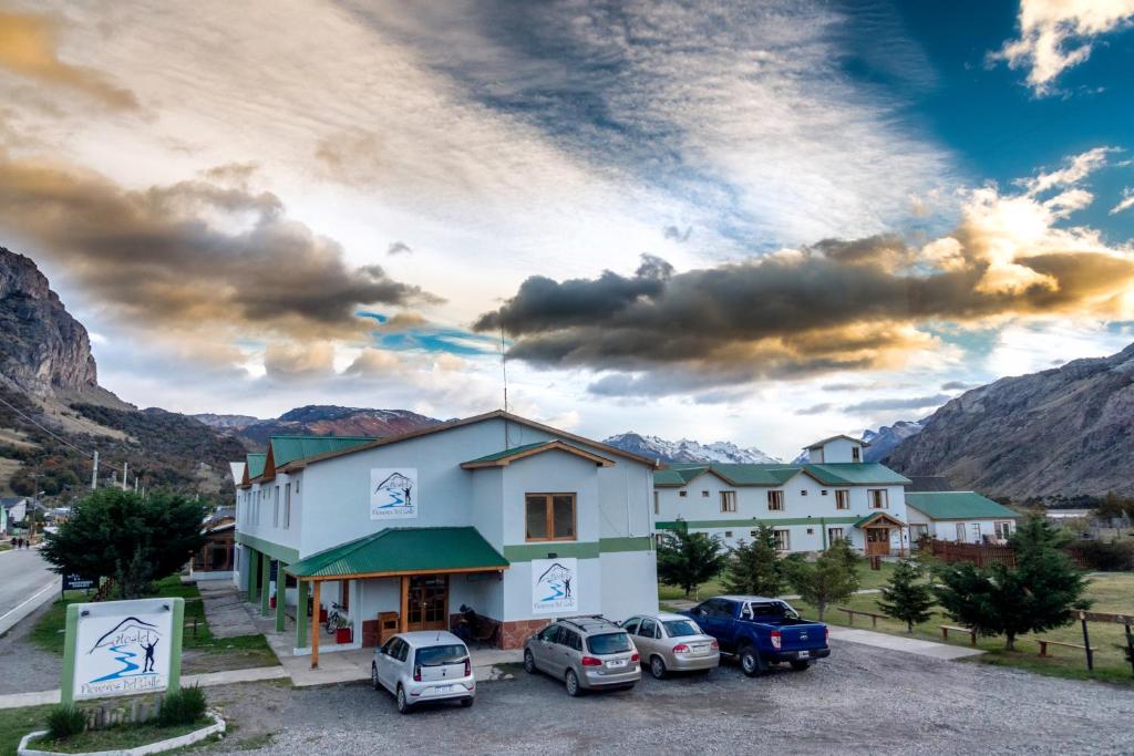 a building with cars parked in a parking lot at Hostel Pioneros del Valle in El Chalten