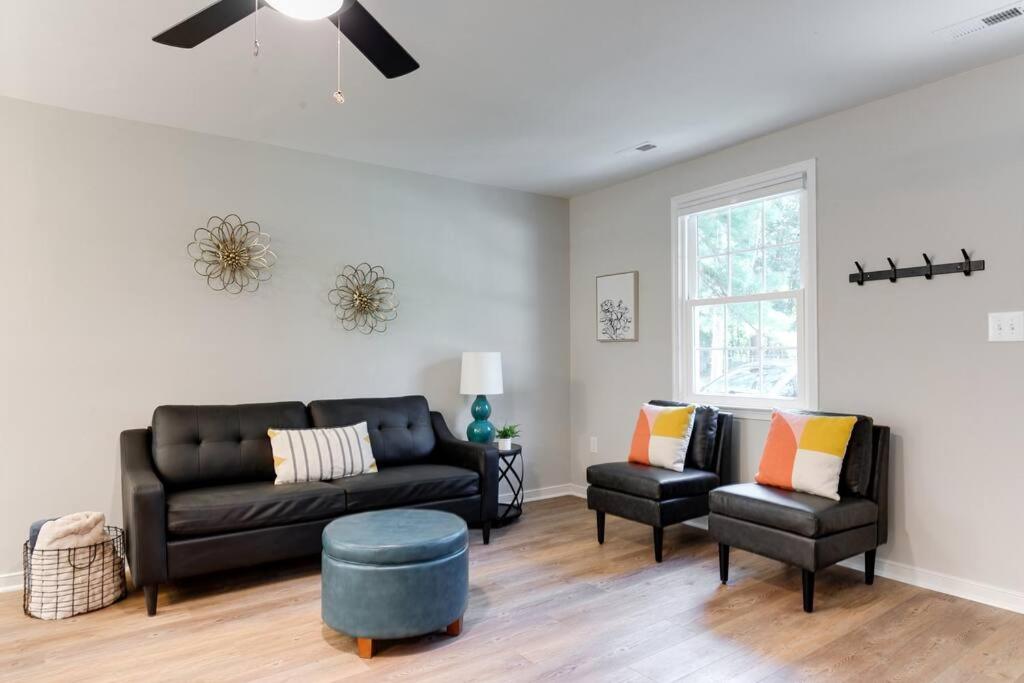 a living room with a black couch and two chairs at Charming, Cheerful 3 Bedroom Home in Richmond, VA! in Richmond