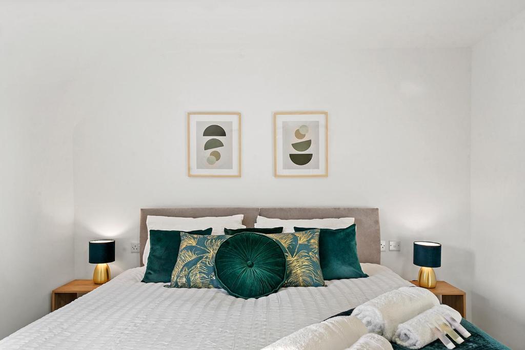 1 dormitorio con 1 cama grande con almohadas verdes en Townhouse in Dartford sleeps 8 with free parking en Dartford