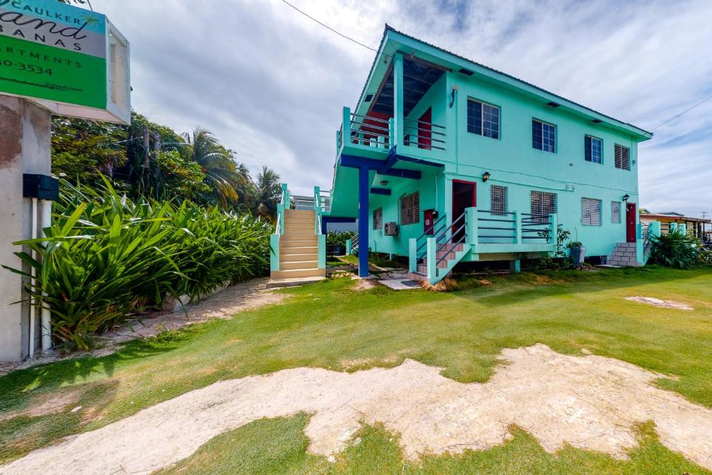 una casa blu con un prato verde davanti di Island Cabanas Gold Standard Certified a Caye Caulker
