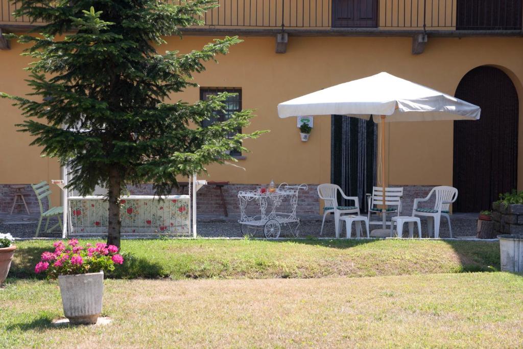 una mesa, sillas y una sombrilla en un patio en B&B Il Giarolo, en Cameriano