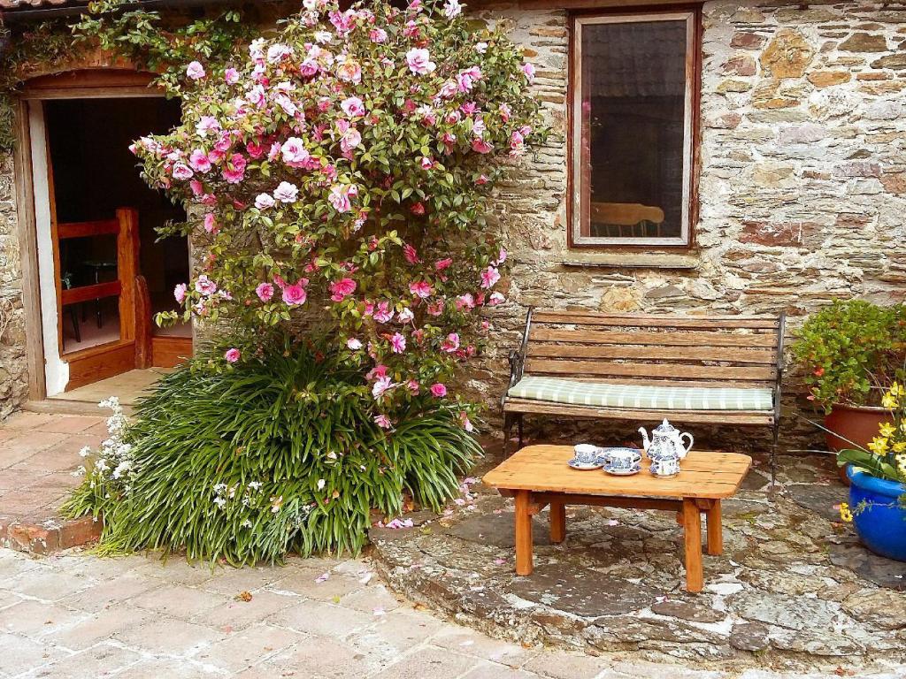 a wooden bench sitting in front of a building with flowers at Cuttrye Old Dairy in Totnes