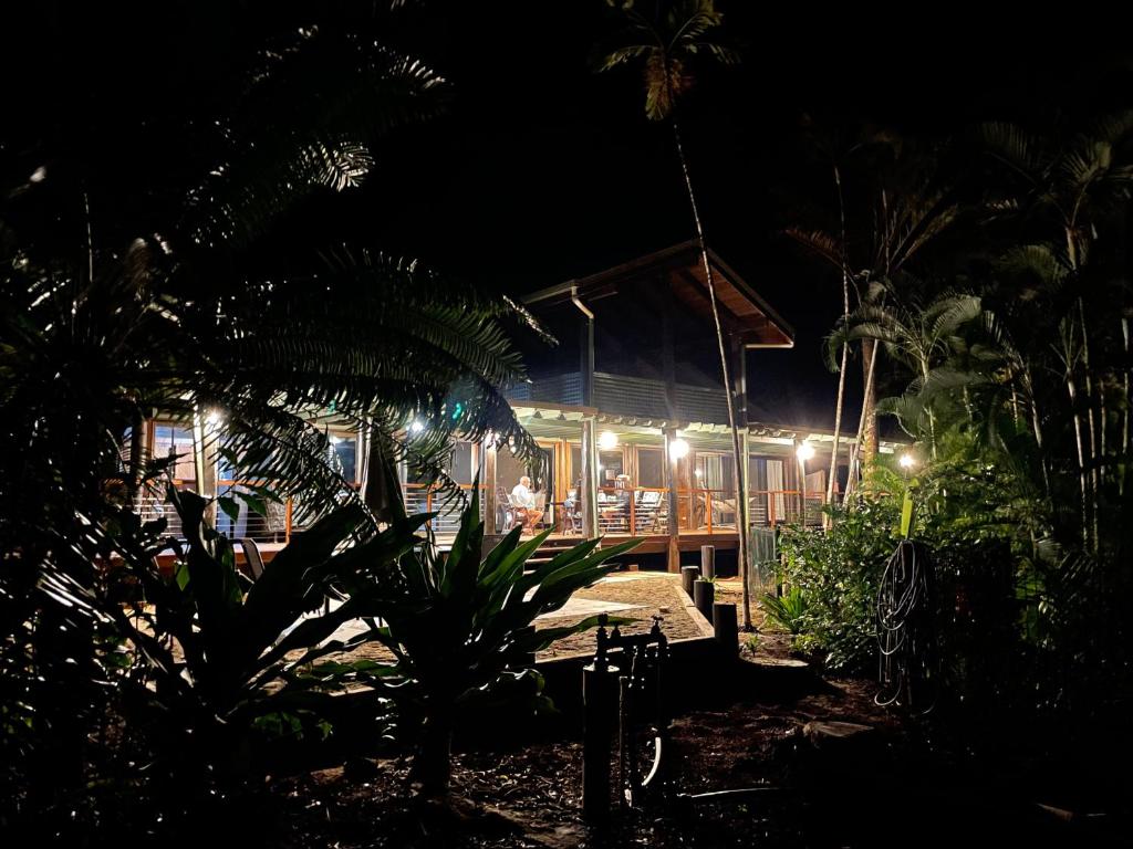 una casa con terraza por la noche con luces en Wait-a-While Eco Retreat en Cow Bay