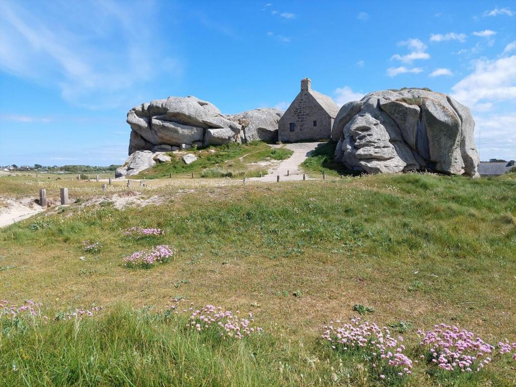 a house on a hill with rocks in a field at Granite stone house with fireplace, Plouguerneau in Plouguerneau