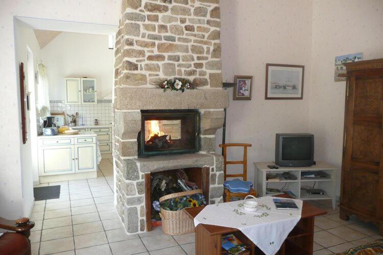 a living room with a stone fireplace with a table at Granite stone house with fireplace, Plouguerneau in Plouguerneau