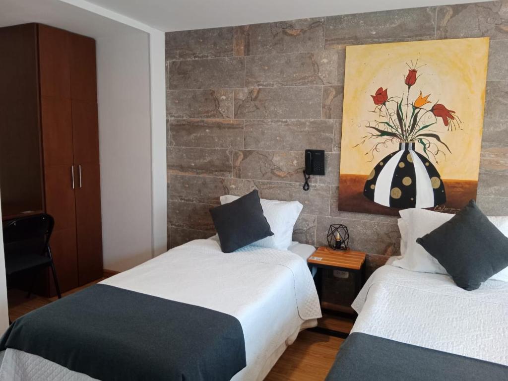 a bedroom with two beds and a painting on the wall at Hotel Posada de Santa Elena in Tunja