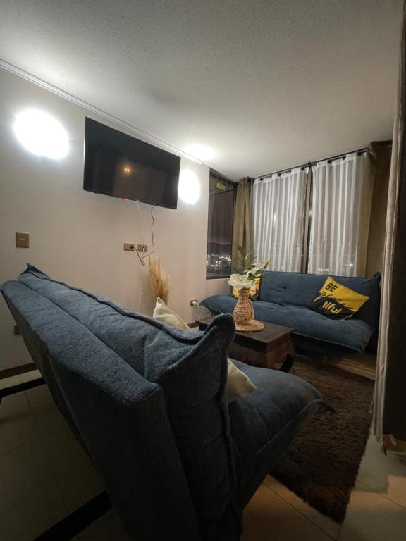 a living room with a blue couch and a table at Fantástico departamento a pasos de playa cavancha con estacionamiento in Iquique